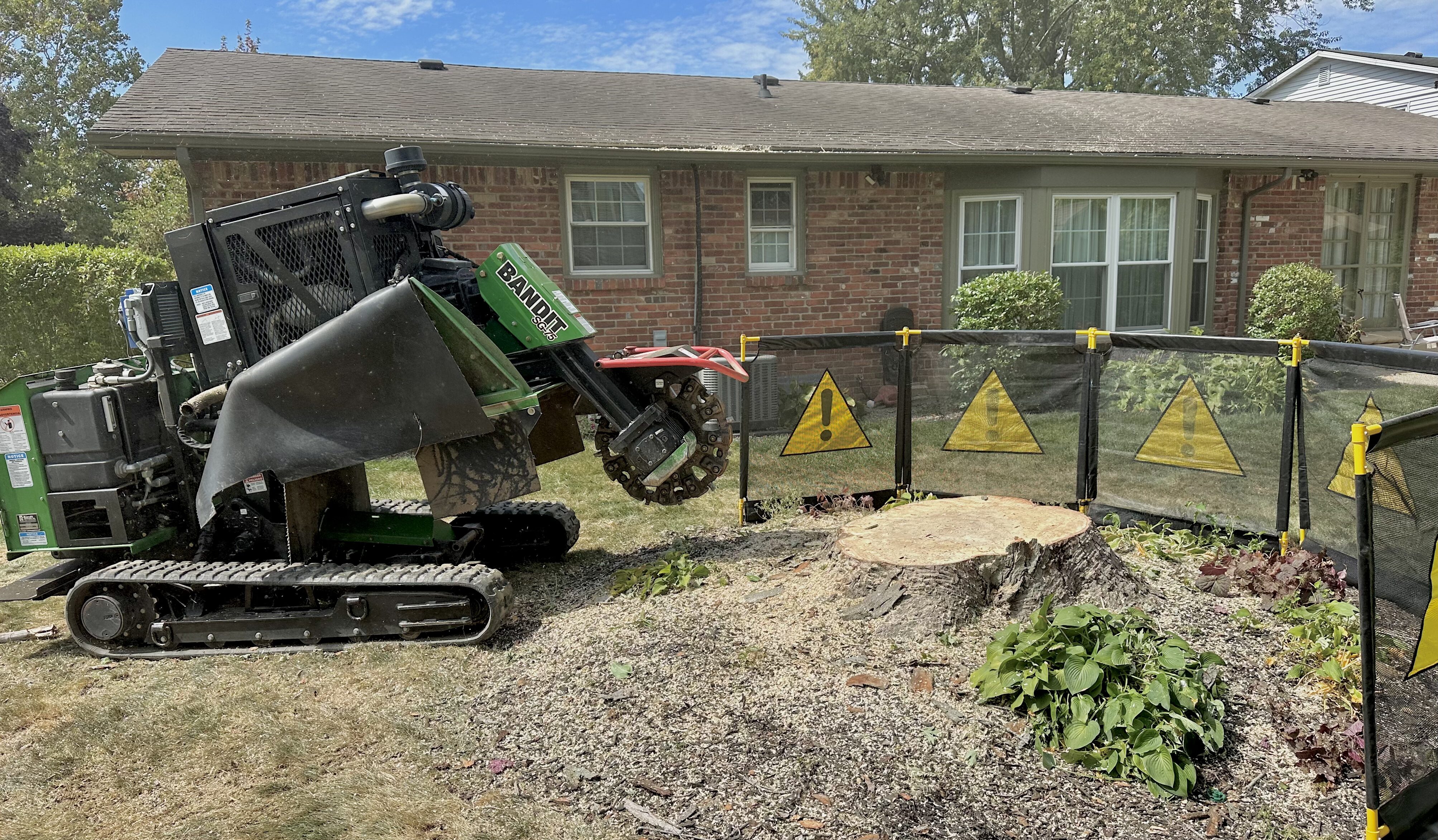 a large green and black stump grinder parked in front of a house